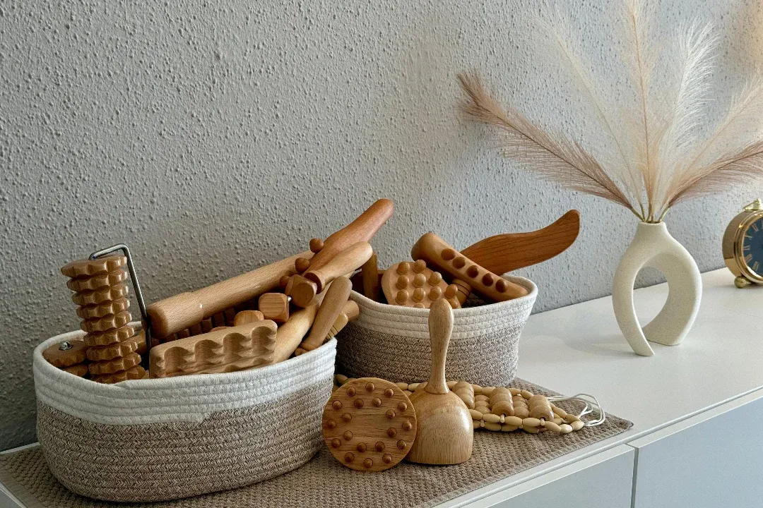 Korb mit den Holzwerkzeugen der Maderotherapie: Rollen, Glocken, Bretter und Noppen aus Holz.